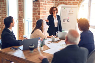 Bir grup iş adamı toplantıda mutlu ve kendinden emin gülümsüyor. Ofisteki pano ve çizelgeleri kullanarak birlikte sunuma bakıyoruz..