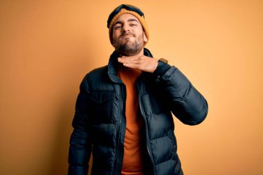 Kar giysileri ve kayak gözlüğü takan, eli bıçak gibi boğazı kesen sakallı yakışıklı kayakçı, saldırganlığı şiddetli bir şiddetle tehdit ediyor.