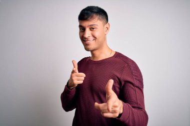 Beyaz izole edilmiş arka plan üzerinde dikilmiş, mutlu ve komik yüzlü genç, Latin asıllı bir adam. İyi enerji ve titreşimler.