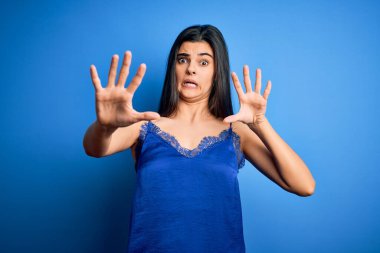 Zarif ve rahat mavi iç çamaşırı giyen genç, güzel esmer kadın korku ifadesinden korkmuş ve dehşete düşmüş. El hareketlerini durdur, şok içinde bağır. Panik konsepti.