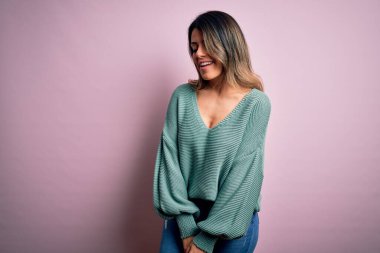 Moda kıyafetleri giyen genç ve güzel bir kadın. Manken, sokak tarzı giyiniyor. Pembe arka planda dikiliyor.