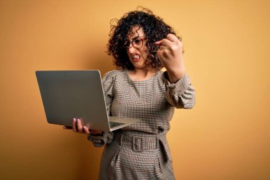 Güzel Arap iş kadını, gözlük takıyor, dizüstü bilgisayar kullanıyor. Sinirli ve sinirli bir şekilde bağırıyor, çıldırıyor ve el kaldırarak bağırıyor. Öfke kavramı.