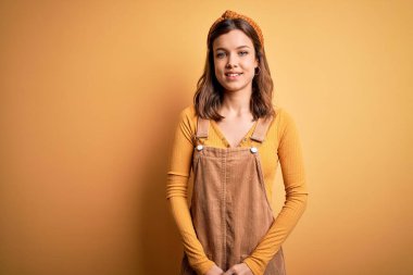 Sarışın, genç ve güzel bir kız. Yüzünde mutlu ve havalı bir gülümsemeyle izole edilmiş sarı bir arka plan üzerinde duruyor. Şanslı kişi..