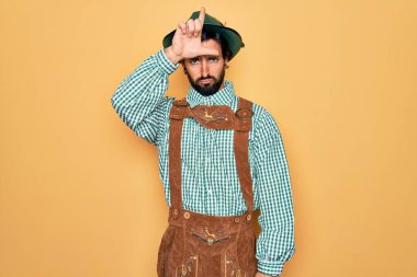 Almanya Festivali için geleneksel Alman Ekim Festivali kıyafeti giyen genç yakışıklı adam parmakları alnında insanlarla alay ediyor ezikçe davranışlar sergiliyor ve alay ediyor..