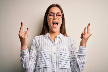 Genç, güzel esmer kadın, beyaz arka plan üzerine günlük gömlek ve gözlük takmış çılgın bir ifadeyle elleri havada rock sembolü yaparak bağırıyor. Müzik yıldızı. Ağır konsept.