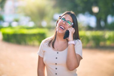 Mutlu ve kendinden emin gülümseyen genç ve güzel bir kadın. Yüzünde gülümsemeyle şehrin akıllı telefonuyla konuşuyor.