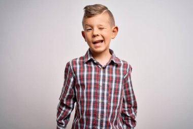 Mavi gözlü, zarif gömlekli, izole edilmiş arka planda duran, seksi bir ifadeyle kameraya bakan, neşeli ve mutlu yüzlü küçük beyaz bir çocuk..