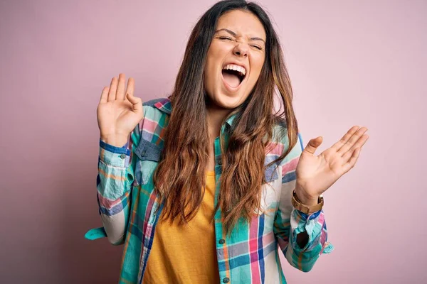 Genç, güzel, esmer bir kadın pembe arka planda dikilmiş kollarını kaldırmış ve gözlerini kapatmış heyecanla haykırarak başarıyı kutluyor. Kazanan konsept