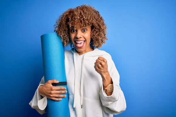 Junge Afrikanisch Amerikanische Sportlerin Hält Yogamatte Über Isoliertem Blauen Hintergrund — Stockfoto