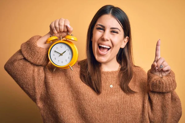 Jonge Mooie Vrouw Met Wekker Staande Geïsoleerde Oranje Achtergrond Verrast — Stockfoto