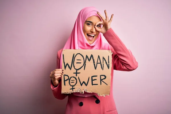 若いです活動家アラブ女性身に着けていますピンクムスリムヒジャーブ保持バナーとともにパワーメッセージとともに幸せな顔笑顔します — ストック写真