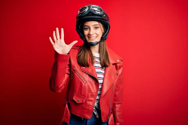 若い美しいブルネットのオートバイのヘルメットと赤いジャケットを身に着けているオートバイの女性が表示され 指番号5で指摘しながら 自信と幸せ笑顔 — ストック写真