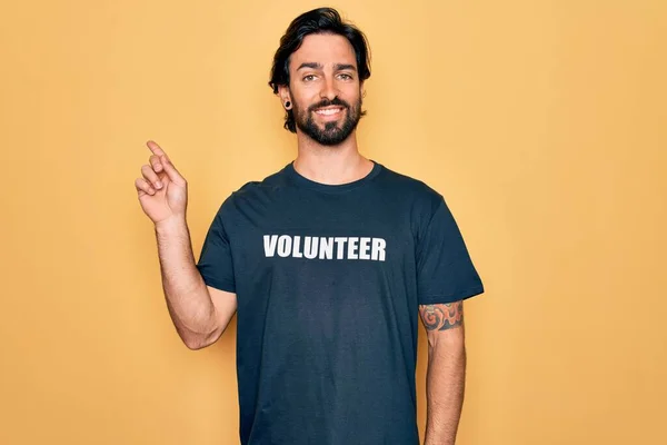ボランティアTシャツを身に着けている若いハンサムなパニックボランティア男性は 幸せと自然な表情で手と指を横に向けて笑顔で陽気に社会的ケアとして — ストック写真
