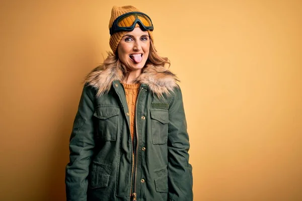 雪のスポーツウェアとスキーゴーグルを身に着けている中世の美しいブロンドのスキーヤー女性は面白い表情で幸せ舌を突き出しています 感情概念 — ストック写真