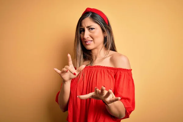 Young beautiful woman colorful summer style over yellow isolated background disgusted expression, displeased and fearful doing disgust face because aversion reaction.