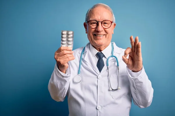 Kıdemli Gri Saçlı Doktor Elinde Ilaç Haplarıyla Mavi Arka Planda — Stok fotoğraf