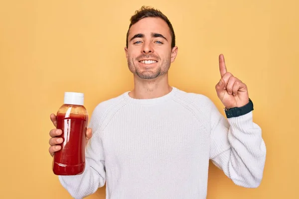 Young Handsome Man Holding Bottle Ketchup Sauce Condiment Yellow Background — Stock Photo, Image