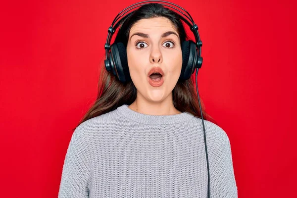 年轻美丽的女孩 戴着现代耳机 在红色背景下听音乐 惊讶的表情 兴奋的脸 — 图库照片