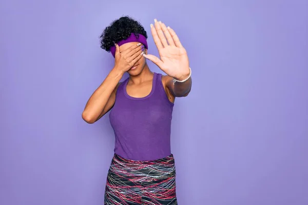 紫色の背景に手で目を覆い 悲しみと恐怖の表情で停止ジェスチャーを行うカジュアルなスポーツウェアを身に着けている美しいアフリカ系アメリカ人アフロ女性 恥ずかしいと否定的な概念 — ストック写真