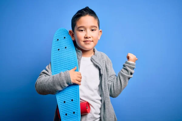 Giovane Bambino Skateboarder Tenendo Skateboard Moderno Sfondo Blu Isolato Puntando — Foto Stock