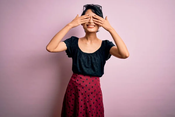孤立したピンクの背景の上に立ち 陽気で面白い手で目を覆うカジュアルなドレスを着た若い美しいアジアの女の子 ブラインドコンセプト — ストック写真