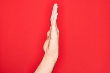 Kafkasyalı bir gencin elleri izole edilmiş kırmızı arka planda parmaklarını gösteriyor. Uzanmış el hareketlerini gösteriyor, itiyor ve durduruyor.