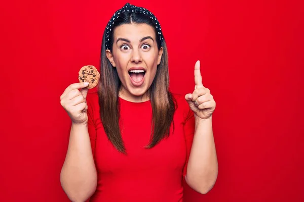 Junge Schöne Brünette Frau Mit Süßem Schokoladenkeks Über Isoliertem Rotem — Stockfoto