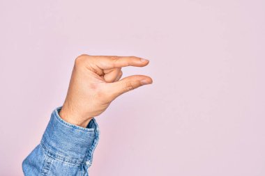 İzole edilmiş pembe arka plan üzerinde parmaklarını gösteren beyaz bir adamın eli. Görünmez bir şeyi alıp, parmaklarıyla uzayı gösteren bir nesneyi tutuyor.