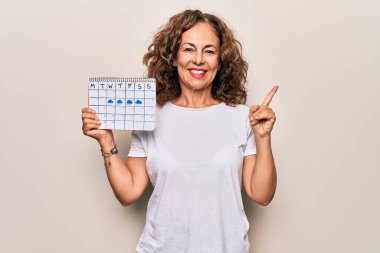 Orta yaşlı, güzel bir kadın, elinde iklim takvimi tutarken bulutlu ve yağmurlu havanın gülümseyişini gösteriyor.