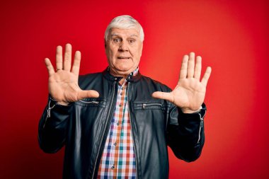 Kıdemli yakışıklı, beyaz gömlekli ve ceketli adam izole edilmiş kırmızı arka planda korku ifadesi karşısında korkmuş ve dehşete düşmüş. El hareketlerini durdur, şok içinde bağır. Panik konsepti.