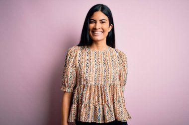 Pembe arka planda zarif bir stil takınan, yüzünde mutlu ve havalı bir gülümsemeyle genç ve güzel bir İspanyol moda kadını. Şanslı kişi..