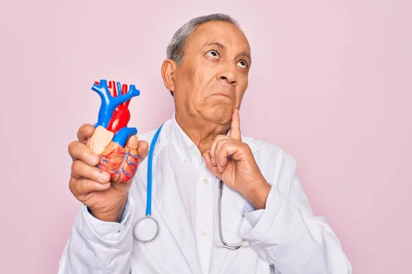 Starszy Lekarz Hoary Noszący Stetoskop Trzymający Plastikowe Serce Nad Różowym — Zdjęcie stockowe