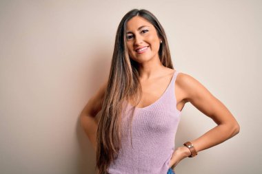 Genç, güzel, esmer bir kadın. Uzun saçlı, izole bir arka planda duruyor. Yüzünde mutlu ve havalı bir gülümseme var. Şanslı kişi..