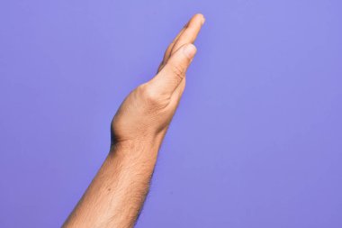 İzole edilmiş mor arka planda parmaklarını gösteren beyaz bir gencin eli uzatılmış el hareketlerini gösteriyor.