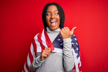 Bağımsızlık gününde Amerika Birleşik Devletleri bayrakları takan Afro-Amerikan vatansever genç bir kadın gülümseyerek yüzünü yana doğru gösteriyor ve gülümsüyor.