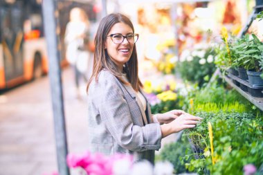 Mutlu ve kendinden emin gülümseyen genç ve güzel bir kadın. Çiçekçiye gülümsüyor.