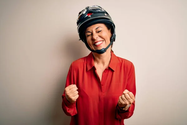 孤立した白い背景の上にオートバイのヘルメットを身に着けている中年のオートバイの女性は非常に幸せと腕を上げて勝者のジェスチャーを行う興奮 笑顔と成功のために叫んで お祝いのコンセプト — ストック写真
