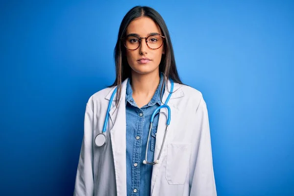 Młoda Piękna Lekarka Nosząca Stetoskop Okulary Niebieskim Tle Zrelaksowana Poważnym — Zdjęcie stockowe