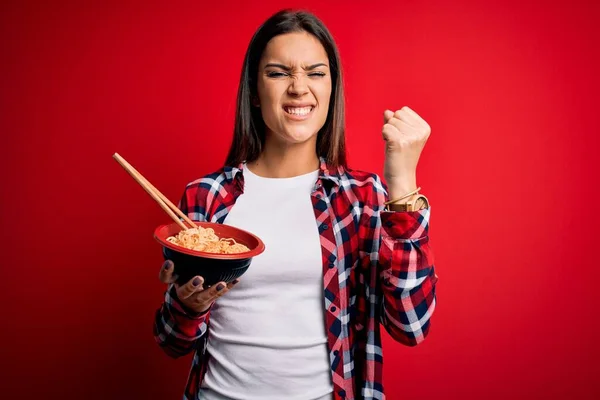 Young Beautiful Brunette Woman Eating Noodles Using Chopsticks Red Background — Stock Photo, Image