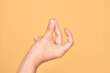 İzole edilmiş sarı arka planda parmaklarını gösteren beyaz bir gencin eli. Başarı için parmaklarını şıklatıyor, kolay ve eliyle sembolü tıklatıyor.