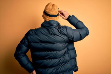 Kar giysileri ve kayak gözlüğü takmış sakallı yakışıklı kayakçı. Geriye doğru kayak gözlüğü takmış, elleri kafasında şüpheyi düşünüyor.