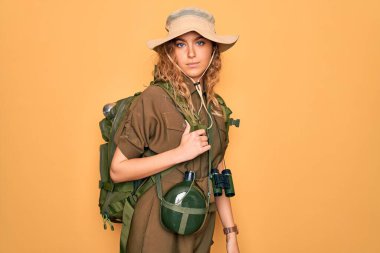 Mavi gözlü, sırt çantası ve su matarası takan genç sarışın kaşif kadın yüzünde ciddi bir ifadeyle rahatladı. Basit ve doğal bir şekilde kameraya bakıyorsun..