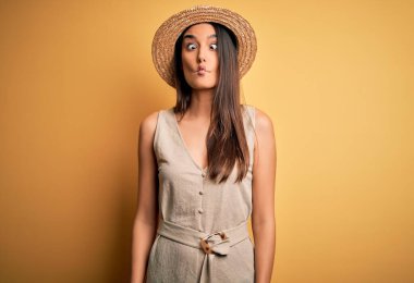 Genç ve güzel esmer kadın tatilde. Günlük elbiseler ve şapkalar giyiyor. Dudaklarıyla balık suratı yapıyor. Komik ifade.