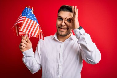 Mavi gözlü genç adam, Amerika Birleşik Devletleri 'nin bayrağını kırmızı izole edilmiş arka planda tutuyordu. Gülümsüyordu.
