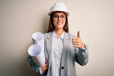 Güvenlik kaskı takan, gözlüklü genç ve güzel bir mimar. Büyük bir gülümsemeyle mutlu.