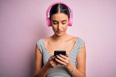 Genç, güzel, esmer, müzik dinleyen, kulaklık ve akıllı telefon kullanan akıllı yüzlü, akıllı yüzlü, ciddi düşünen bir kadın.