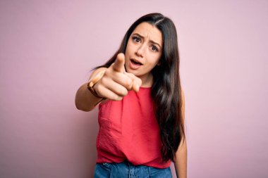 Genç esmer kadın pembe izole edilmiş arka plan üzerine gündelik bir tişört giyiyor. Kameraya kızgın ve sinirli olduğunu gösteriyor.