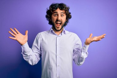 Mor arka plan üzerinde duran sakallı genç ve yakışıklı iş adamı çılgın ve başarıyı kollarını kaldırıp heyecanla haykırarak kutluyor. Kazanan konsept