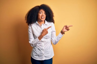 Sarı arka planda duran afro saçlı, güzel Afro-Amerikan zarif bir kadın. Endişeli ve gergin bir tarafı var. Endişeli ve şaşırmış bir ifade.