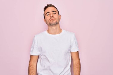 Mavi gözlü yakışıklı bir adam pembe arka planda duran günlük beyaz tişört giyiyor. Yüzünde ciddi bir ifadeyle rahatlamış. Basit ve doğal bir şekilde kameraya bakıyorsun..